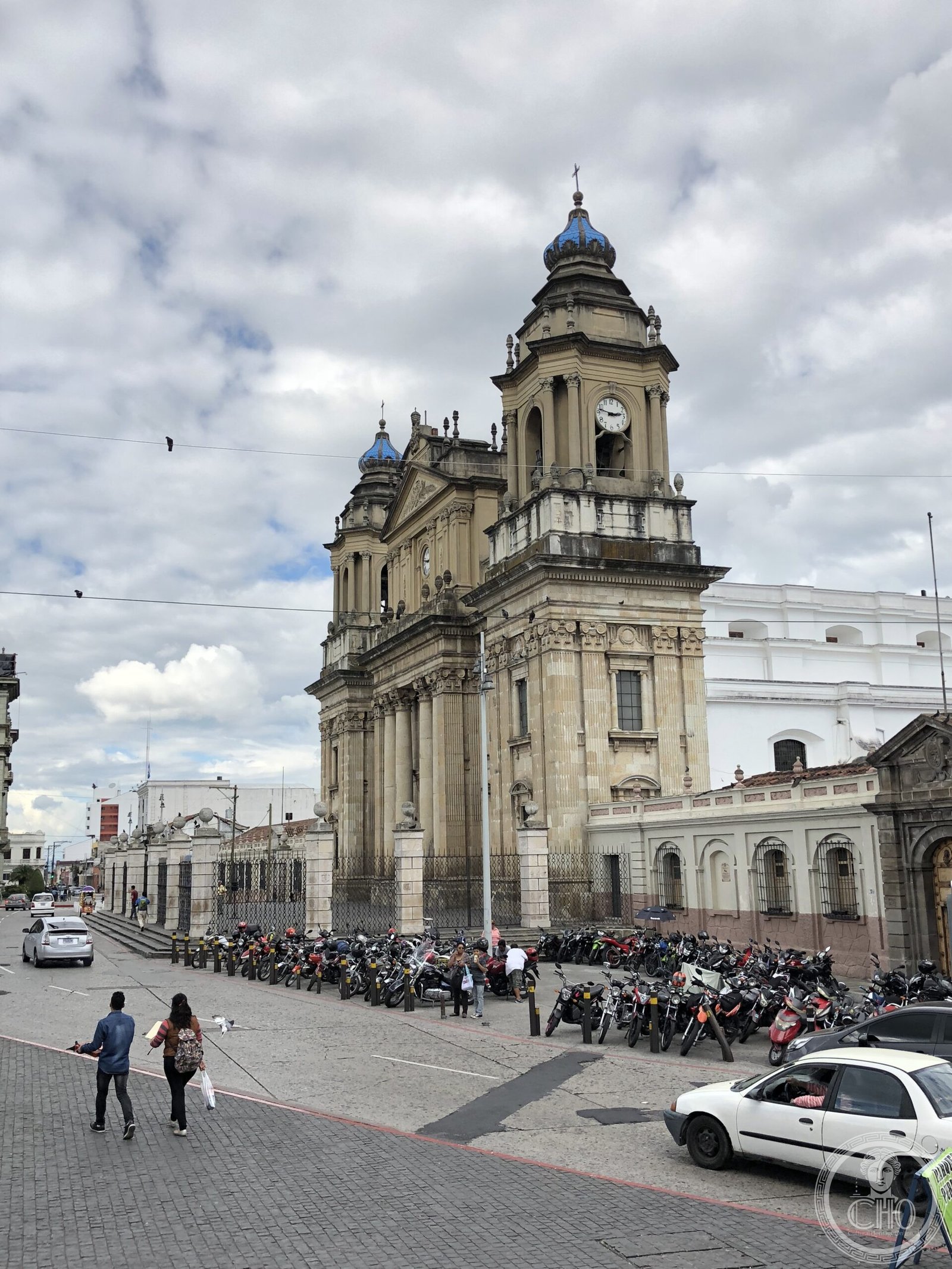 Metropolitan Cathedral of Guatemala City, a neoclassical stone facade with twin bell towers topped by blue-tiled onion domes, on the Plaza de la Constitución