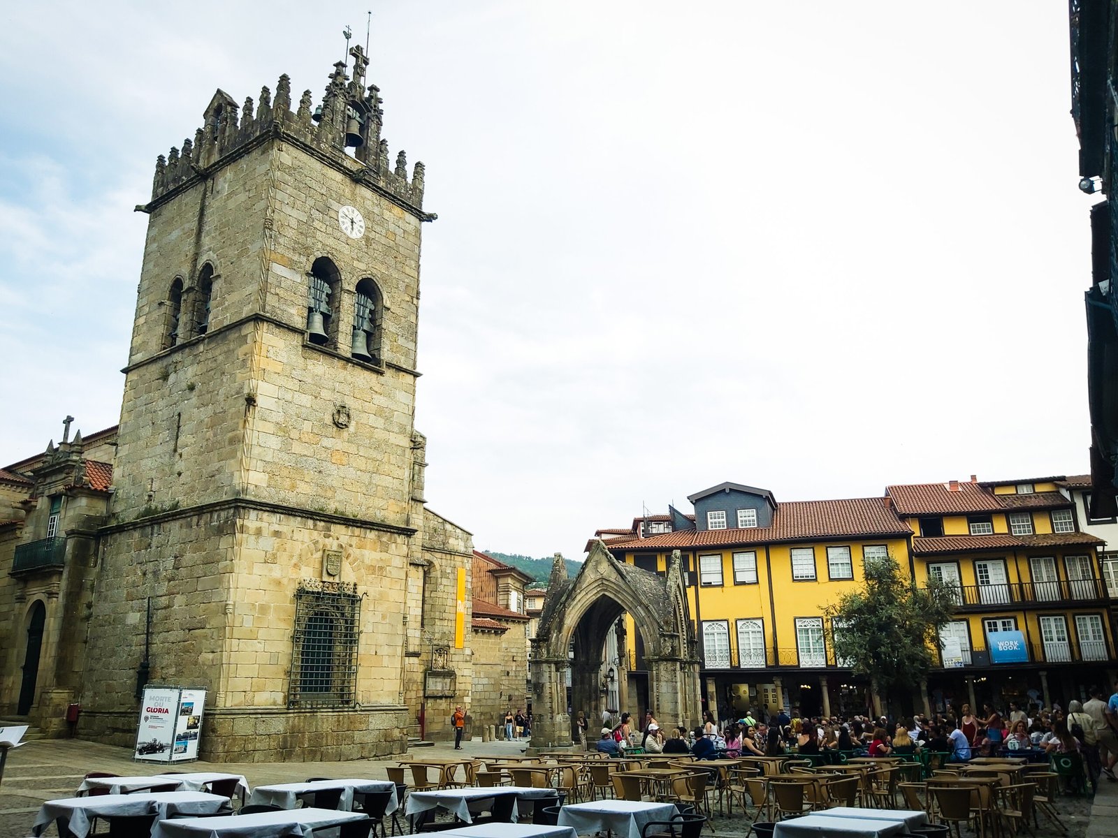 The Gothic bell tower of the Church of Our Lady of Oliveira in Guimar&atilde;es, with the Padr&atilde;o do Salado canopy and the yellow houses of the Largo da Oliveira