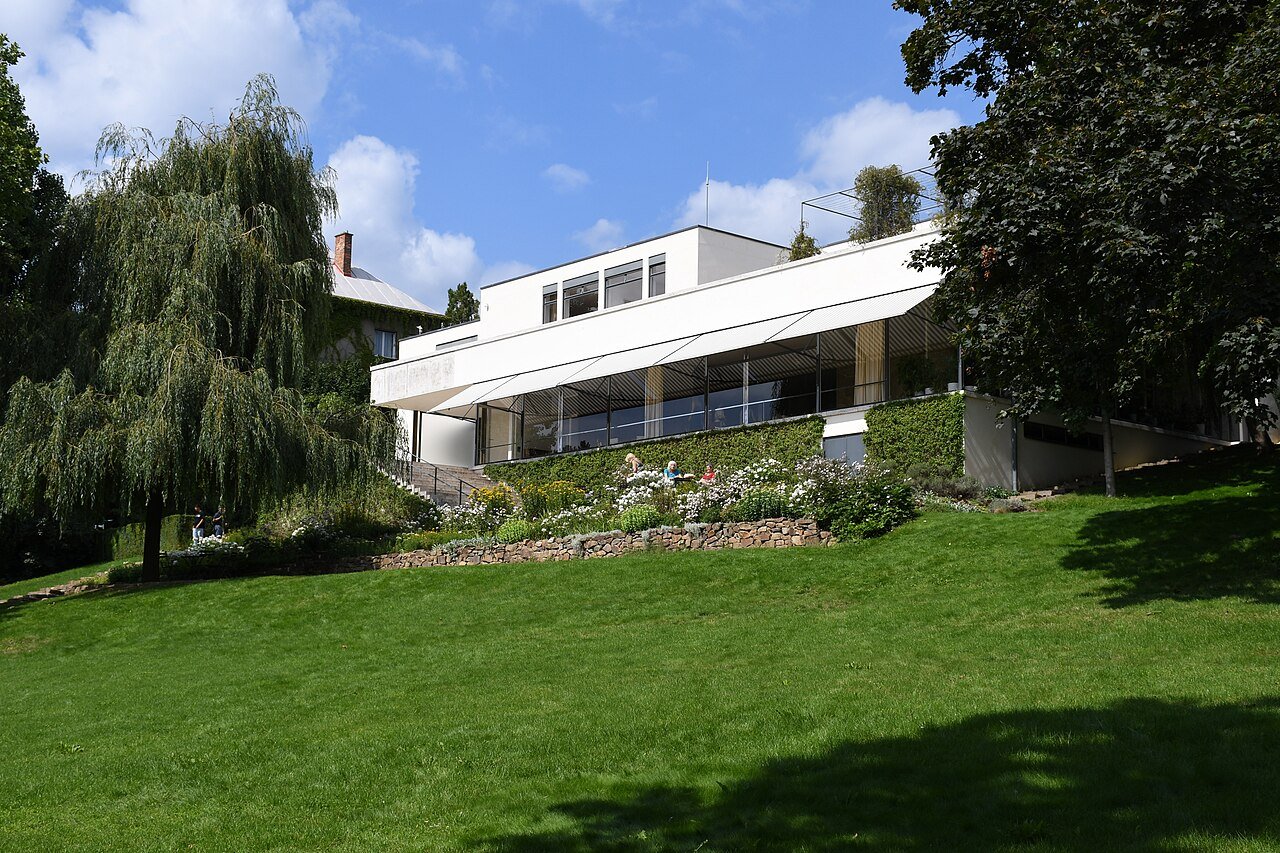 Villa Tugendhat seen from the garden, its long white facade and glass walls stepping down the slope