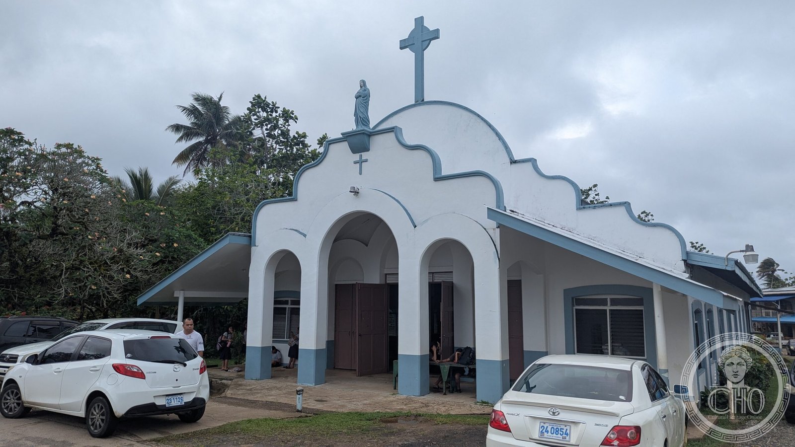Church of Our Lady of Mercy in Kolonia, Pohnpei, a white mission-revival church with light-blue trim, a triple-arched portico, and a statue of the Virgin Mary above the entrance