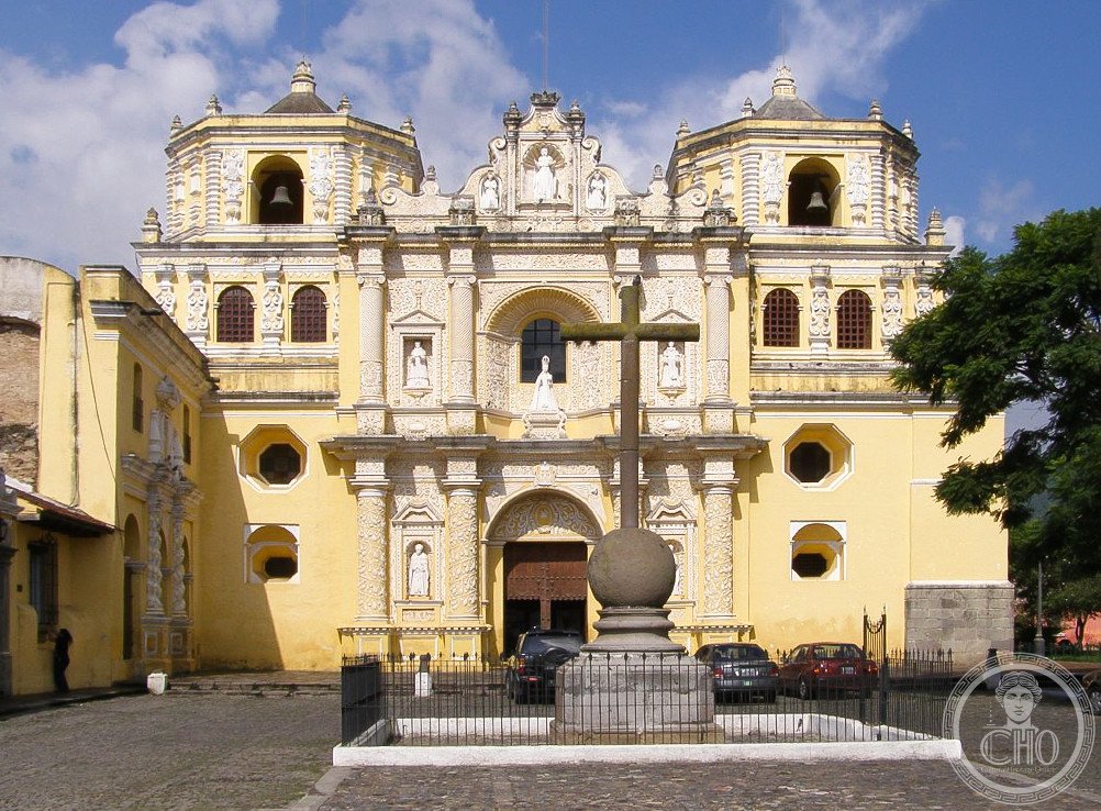 The Church of La Merced in Antigua Guatemala, its ornate yellow and white Baroque stucco facade built 1749-1767 with deliberately thick walls and a low profile to survive earthquakes