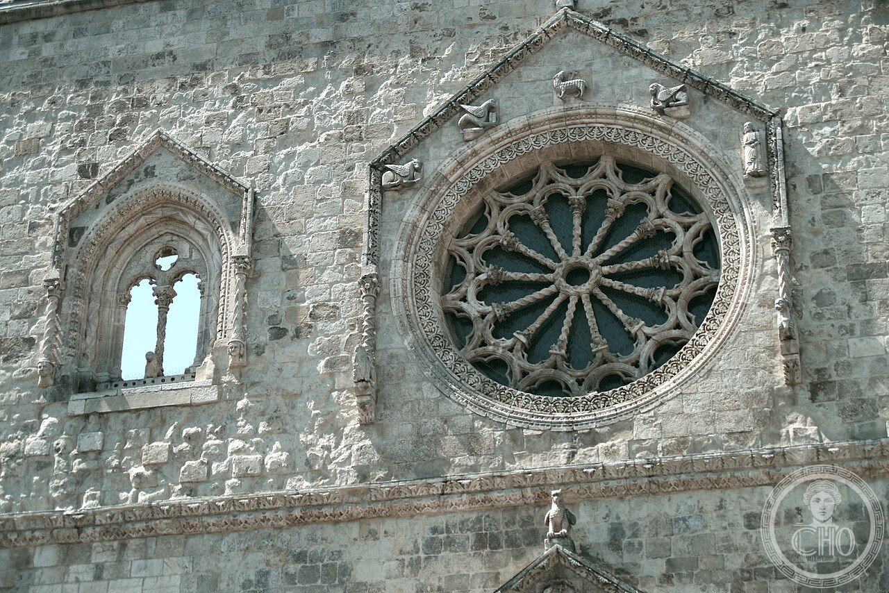 Exterior facade of the Cathedral of San Pardo in Larino, Molise, Italy, consecrated 1319, with its distinctive thirteen-ray rose window and asymmetrical plan built over an earlier medieval structure