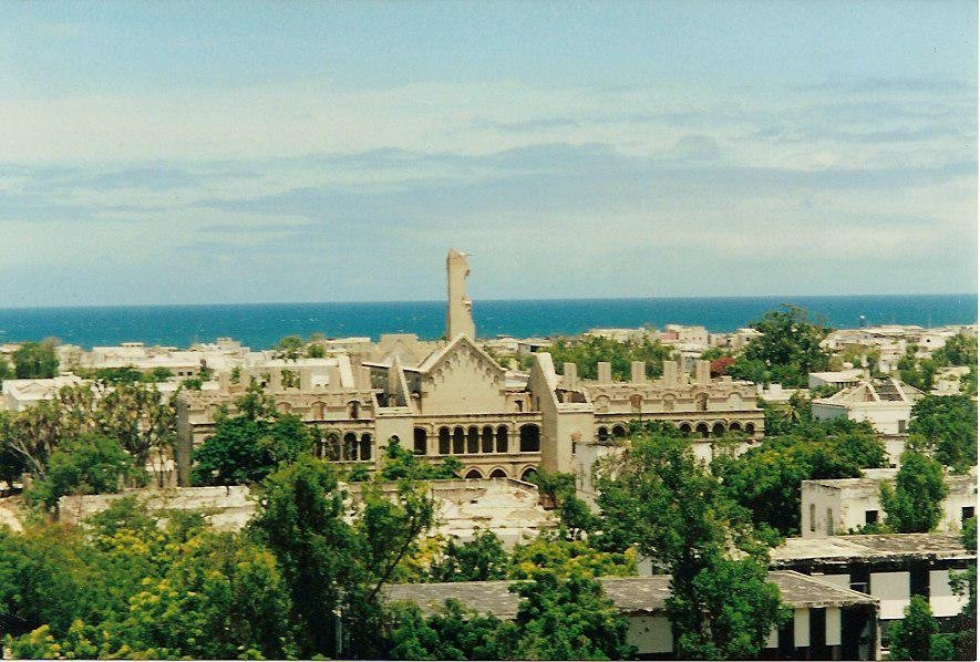 The ruined cathedral of Mogadishu seen over the rooftops of the city, with the Indian Ocean behind