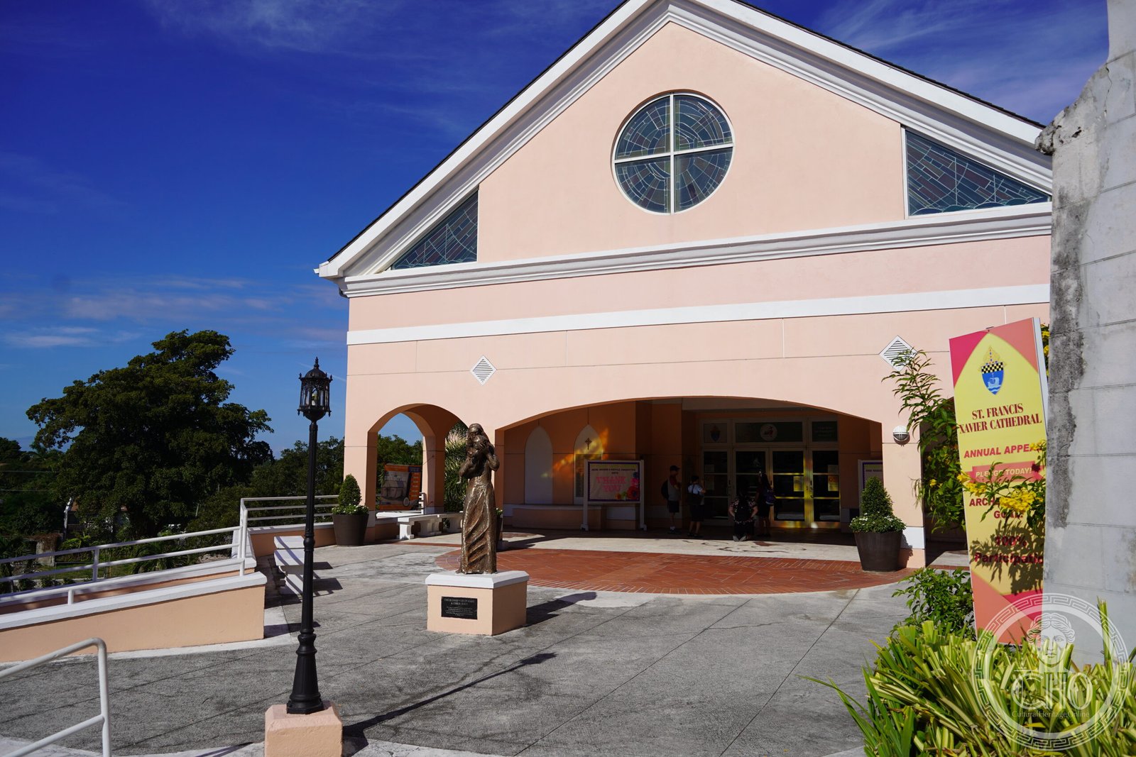 St. Francis Xavier Cathedral in Nassau, The Bahamas, a pink gable facade with a round stained-glass window and a bronze statue in the courtyard