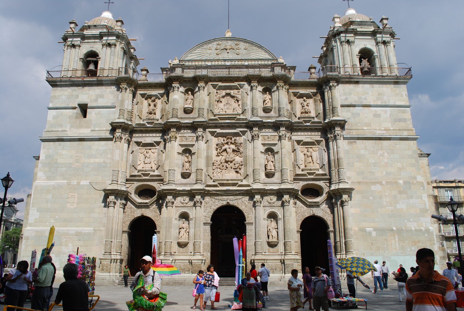 Green cantera stone facade of Oaxaca Cathedral, Mexico, with carved Assumption relief and squat twin bell towers