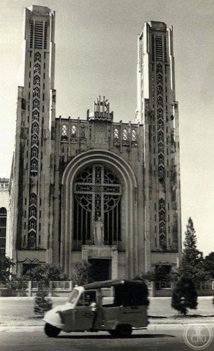 Historical black-and-white photograph of Notre-Dame Cathedral, Phnom Penh, showing its twin Art Deco-Gothic towers and arched cross window before its 1975 demolition
