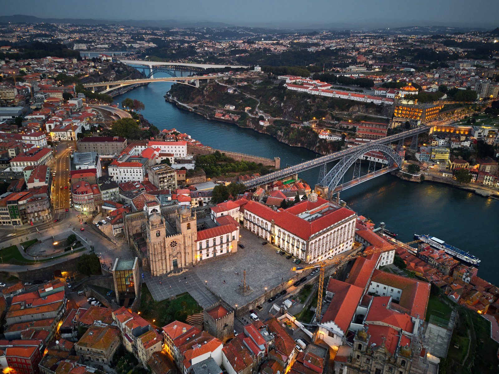 Porto Cathedral, a fortress-like granite church with two cupola-topped towers, on its hilltop terrace above the Douro and the Dom Lu&iacute;s I Bridge