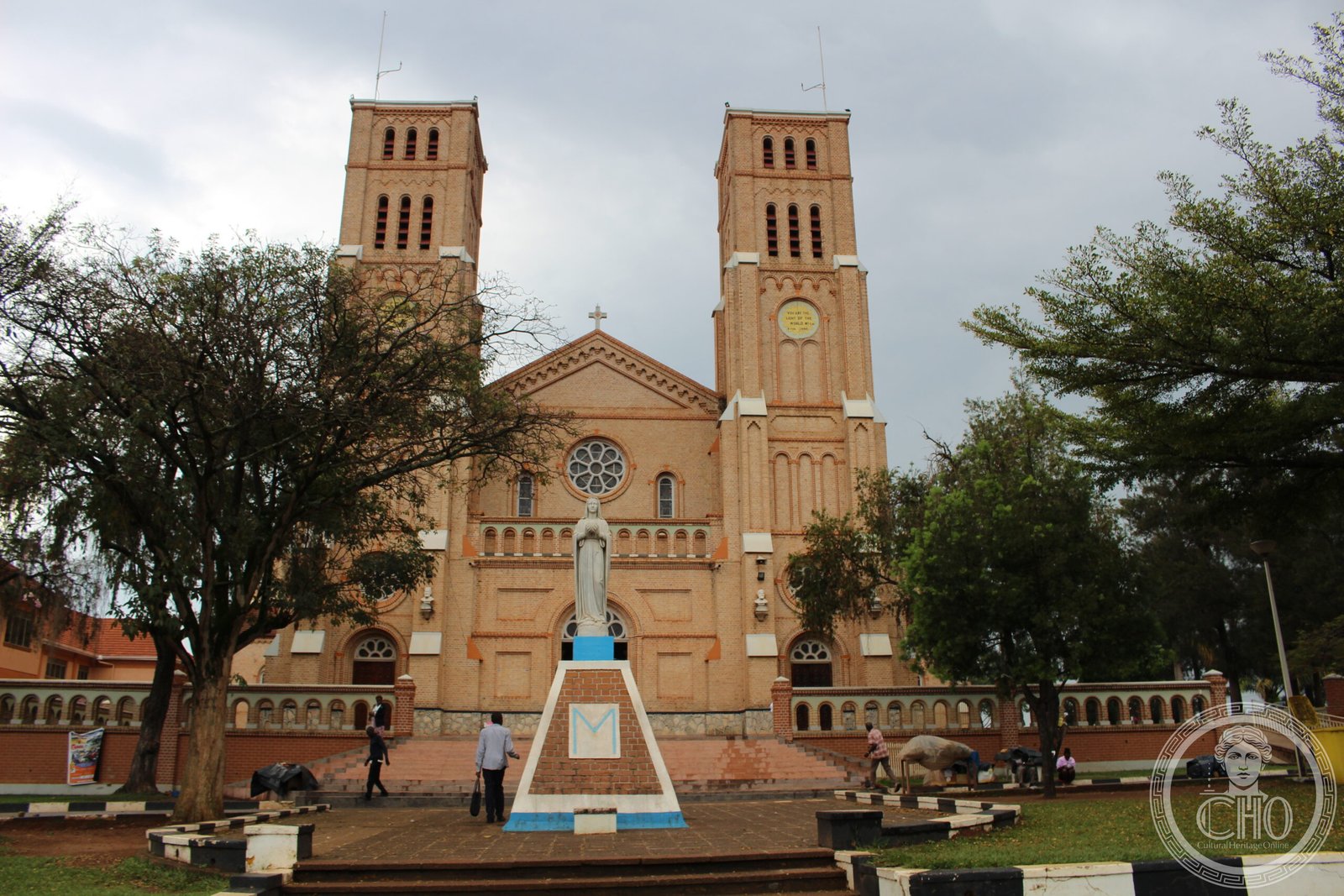 Rubaga Cathedral in Kampala, Uganda, a twin-towered pink brick Romanesque church on a hilltop, with a statue of the Virgin Mary in front