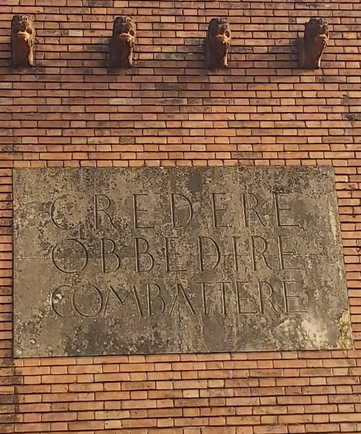 Ex Casa del Fascio — Rubano (Quirino De Giorgio, 1937–1939) — The stone slab in close-up: CREDERE OBBEDIRE COMBATTERE, incised in Roman capitals.