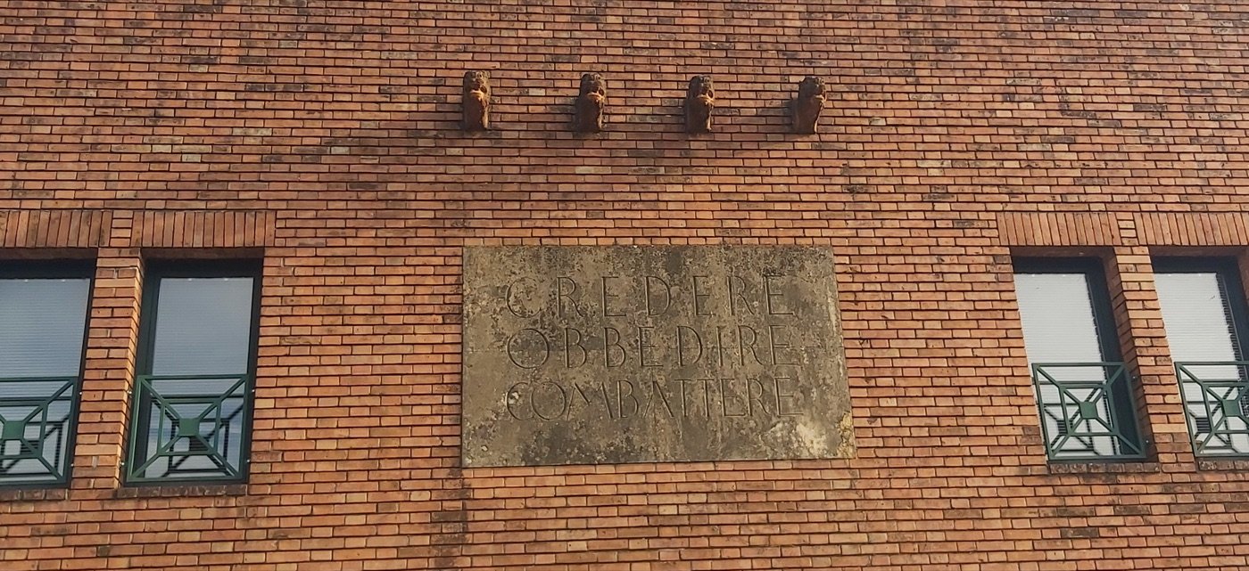 Ex Casa del Fascio — Rubano (Quirino De Giorgio, 1937–1939) — The four fasces consoles and the slogan slab, set between the upper windows.
