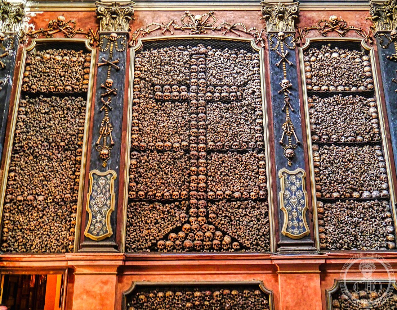 The Ossuary Chapel of San Bernardino alle Ossa in Milan, Italy, its walls covered in human skulls and bones beneath a 1695 ceiling fresco by Sebastiano Ricci depicting the Triumph of Souls