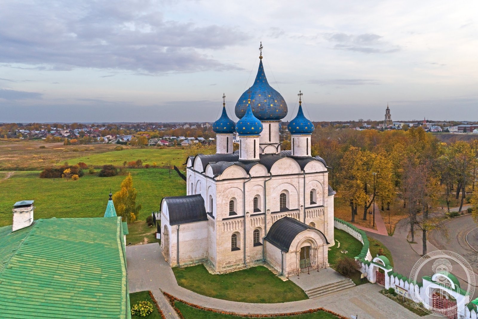 Aerial autumn view of the Cathedral of the Nativity of the Theotokos in the Suzdal Kremlin, Russia, showing its white walls and five deep-blue, gold-starred onion domes