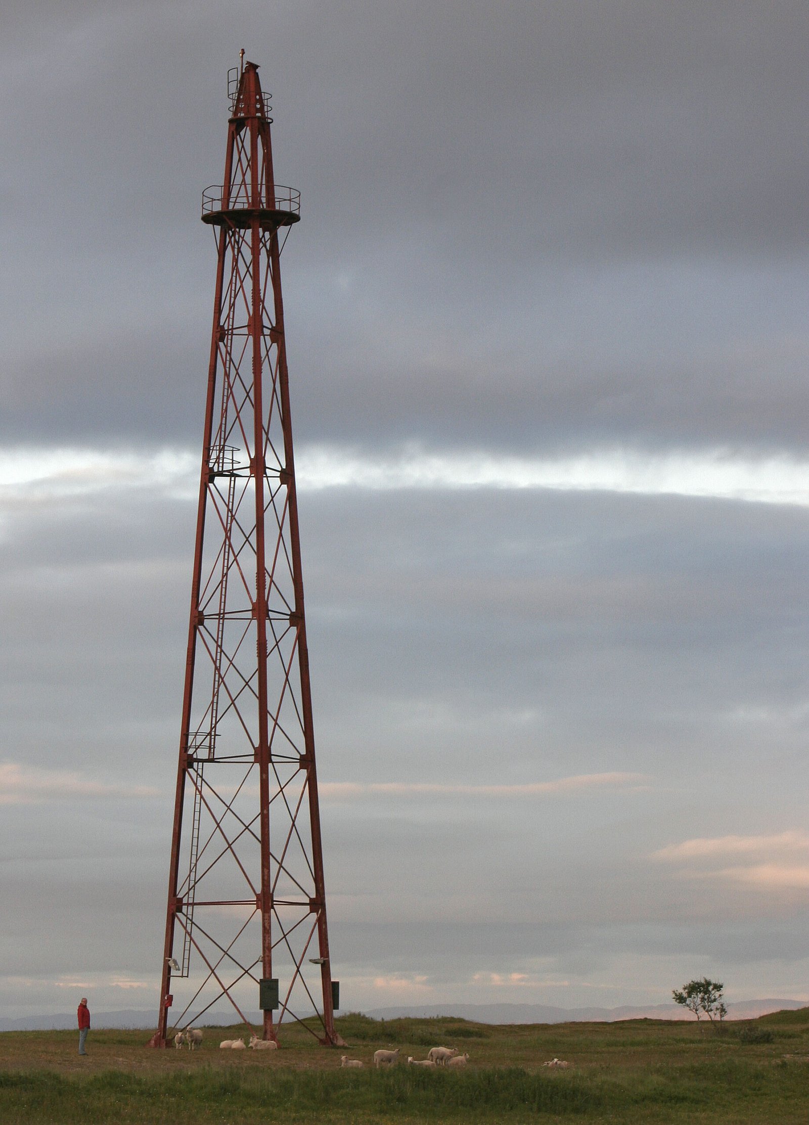 Red lattice airship mooring mast standing on flat grassland on Vadsoya island