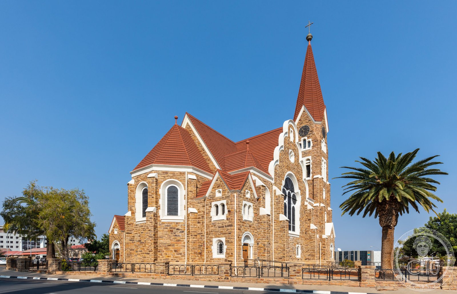 Christuskirche in Windhoek, Namibia, a golden sandstone Gothic Revival and Art Nouveau church with a pointed spire, standing on a central traffic circle