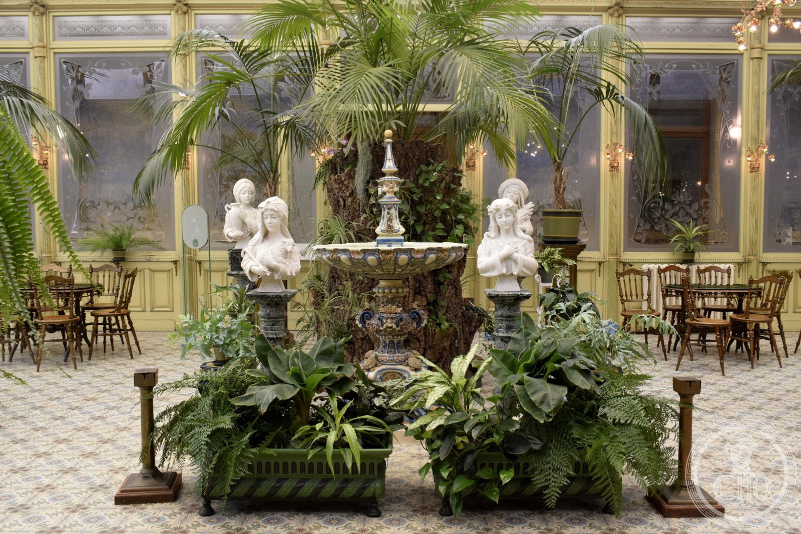Ceramic fountain with marble busts and potted palms inside the Winter Garden of the Ursulines