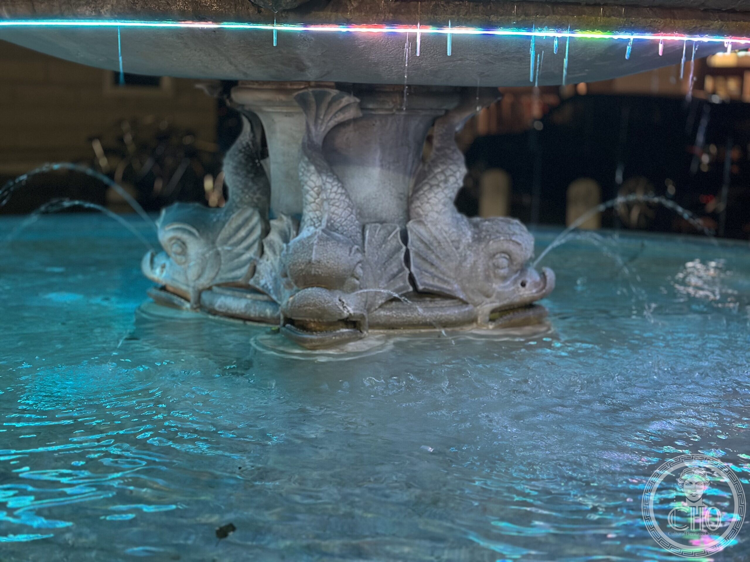 Close view at night of the dolphin figures supporting the middle basin of the fountain of Piazza San Leonardo, Treviso