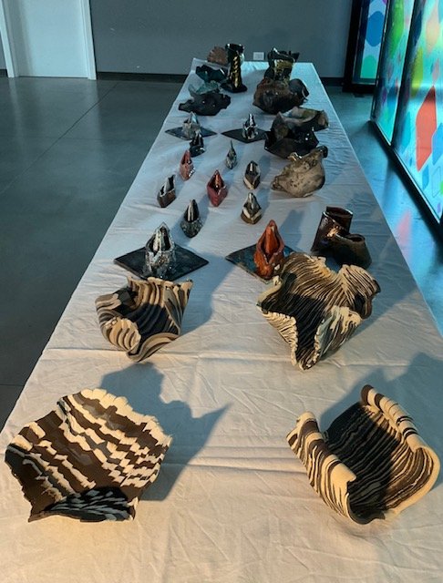 Series of ceramic sculptures on a table, with irregular shapes and striped patterns
