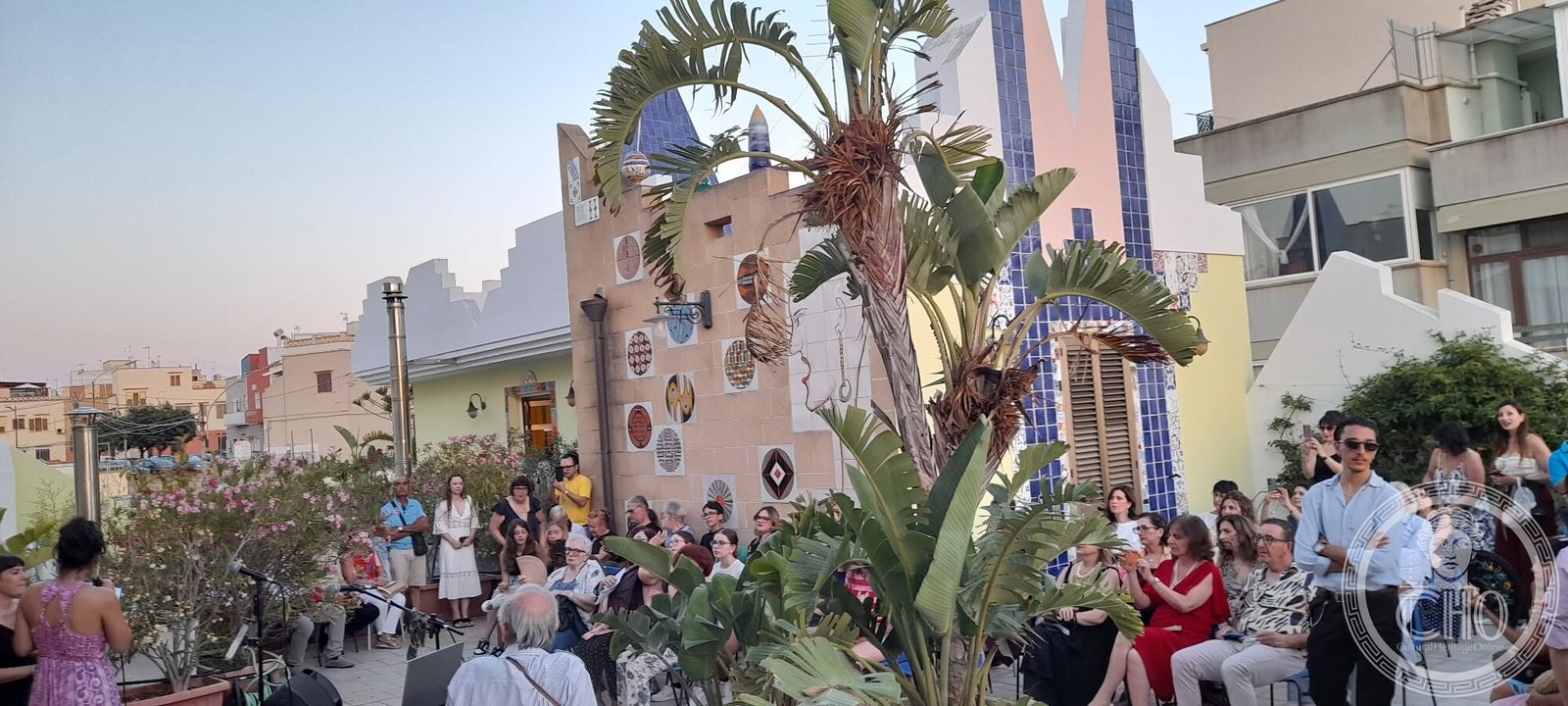 Audience seated in the majolica-decorated roof garden of the Casa degli Artisti at sunset
