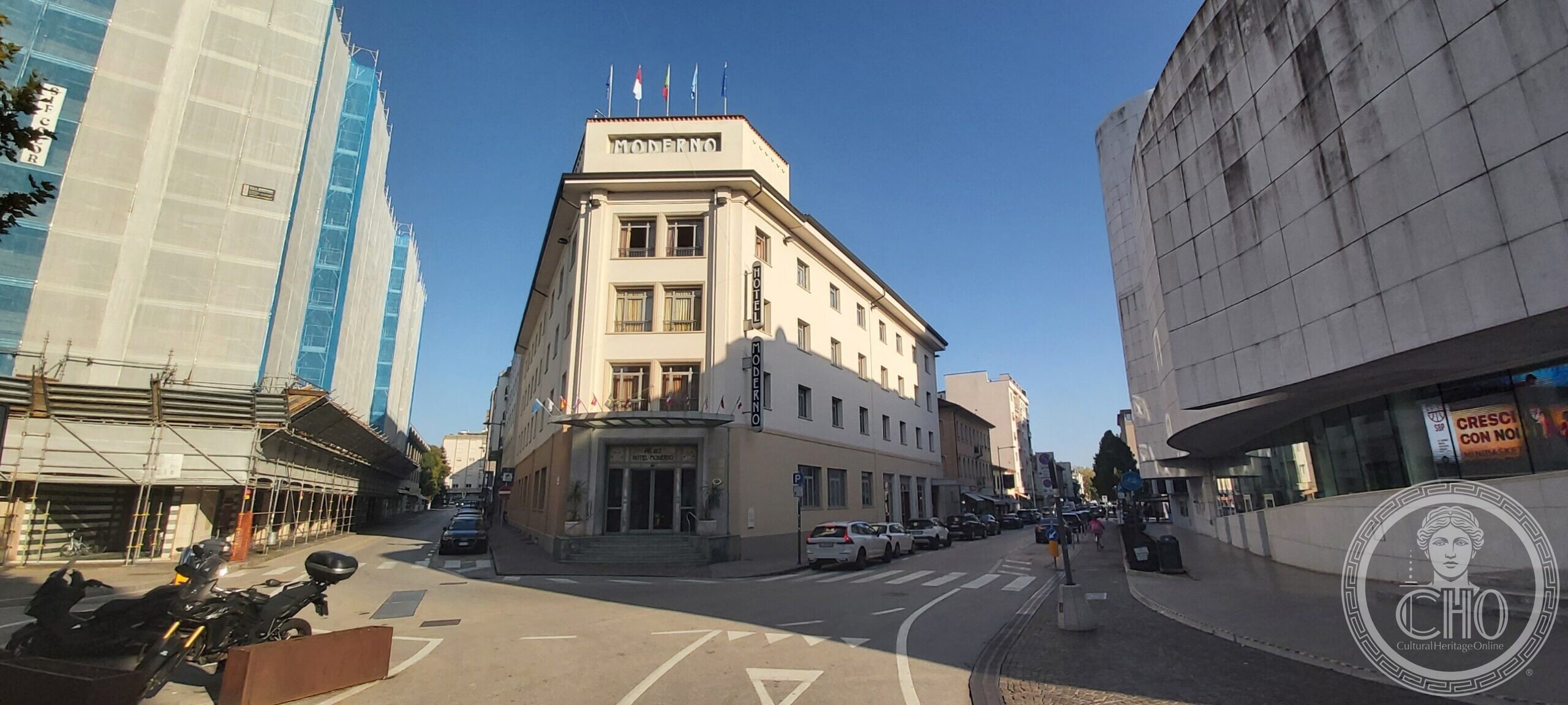 The Albergo Moderno in Pordenone: a pale four-storey hotel on an acute corner, with a rooftop box lettered MODERNO and a vertical HOTEL MODERNO sign