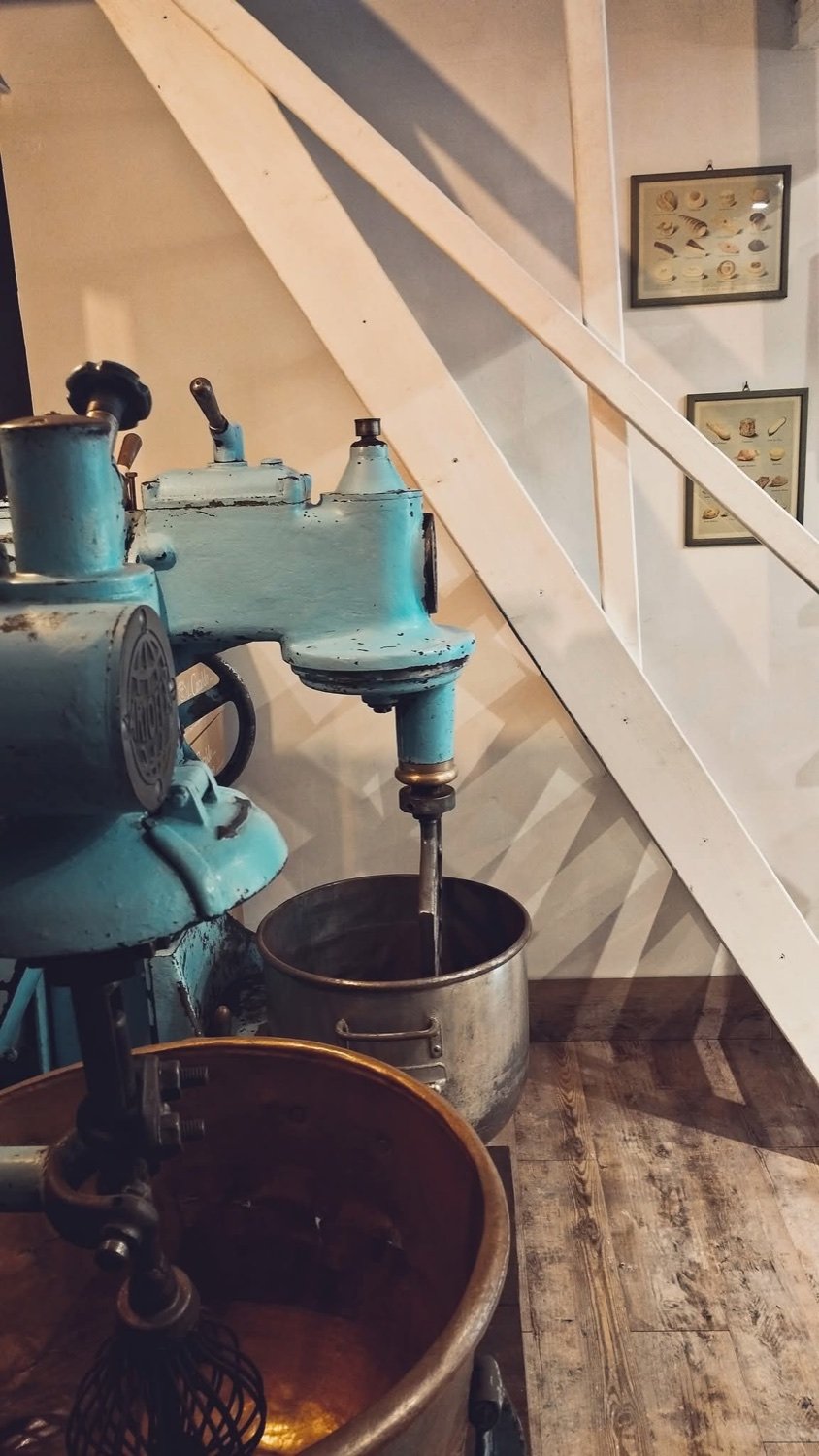 Mixer with a steel bowl standing under a wooden staircase
