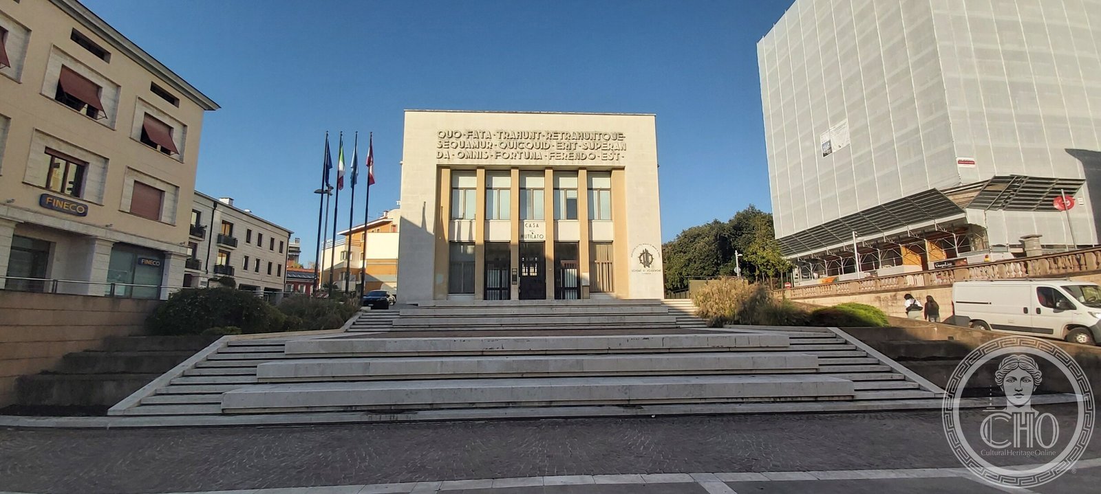 The Casa del Mutilato seen across the square, raised above a broad shallow flight of steps with four flagpoles beside it