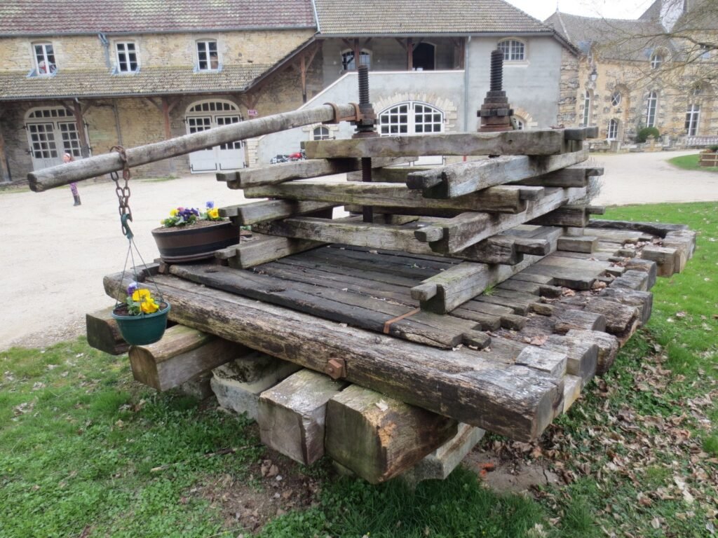 A large timber beam wine press standing in the courtyard of the château