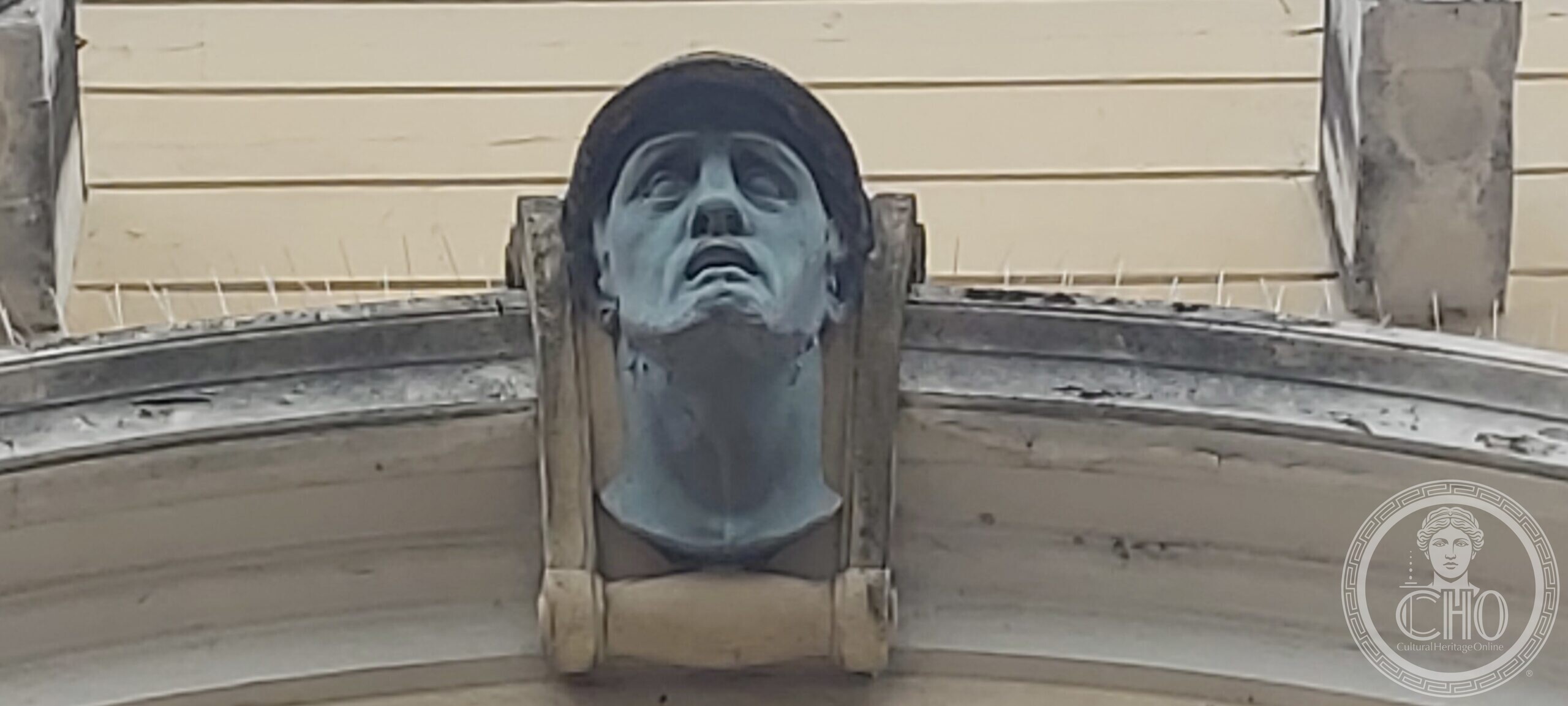 Bronze keystone mask of a helmeted soldier with upturned face and open mouth on the Casa del Mutilato in Padua