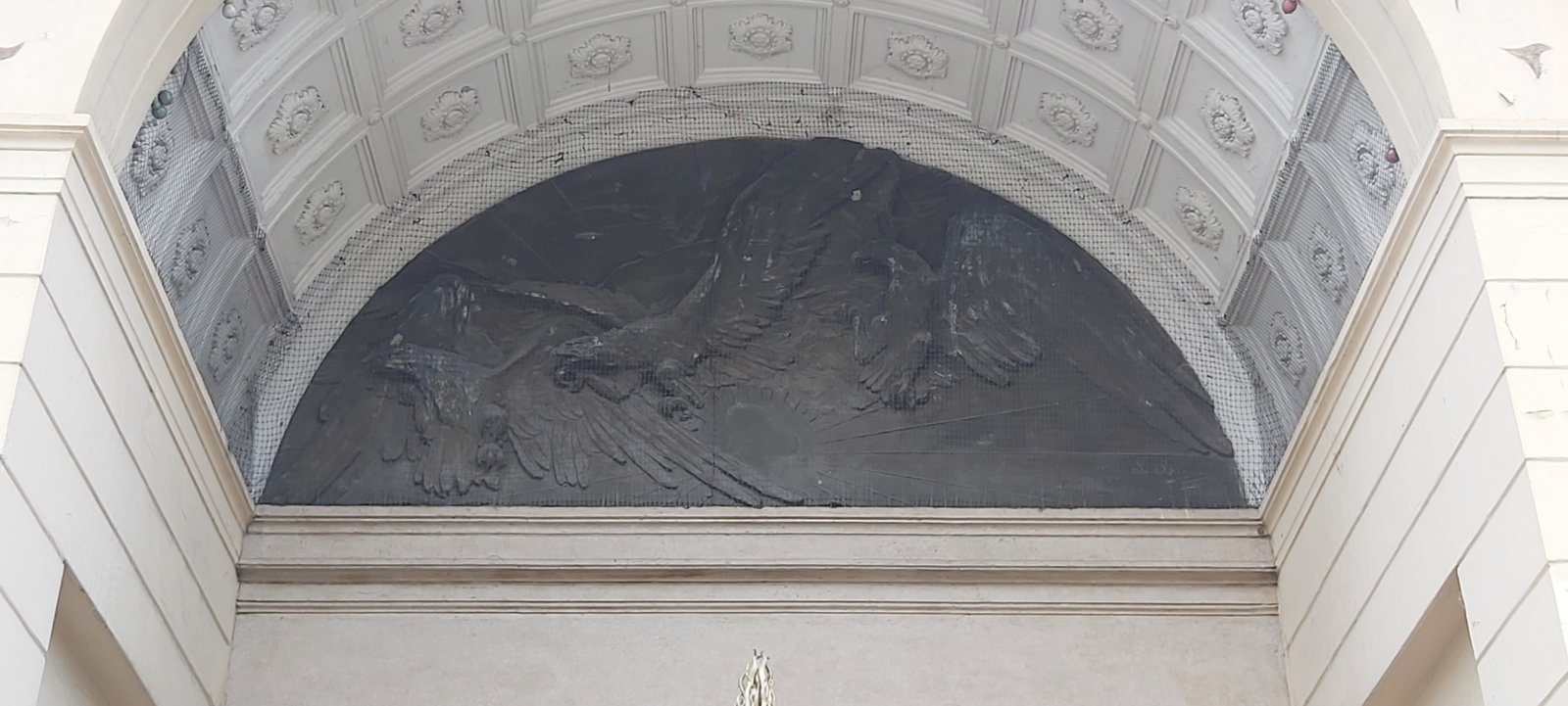 Bronze relief of wounded eagles in flight in the lunette above the entrance atrium of the Casa del Mutilato in Padua