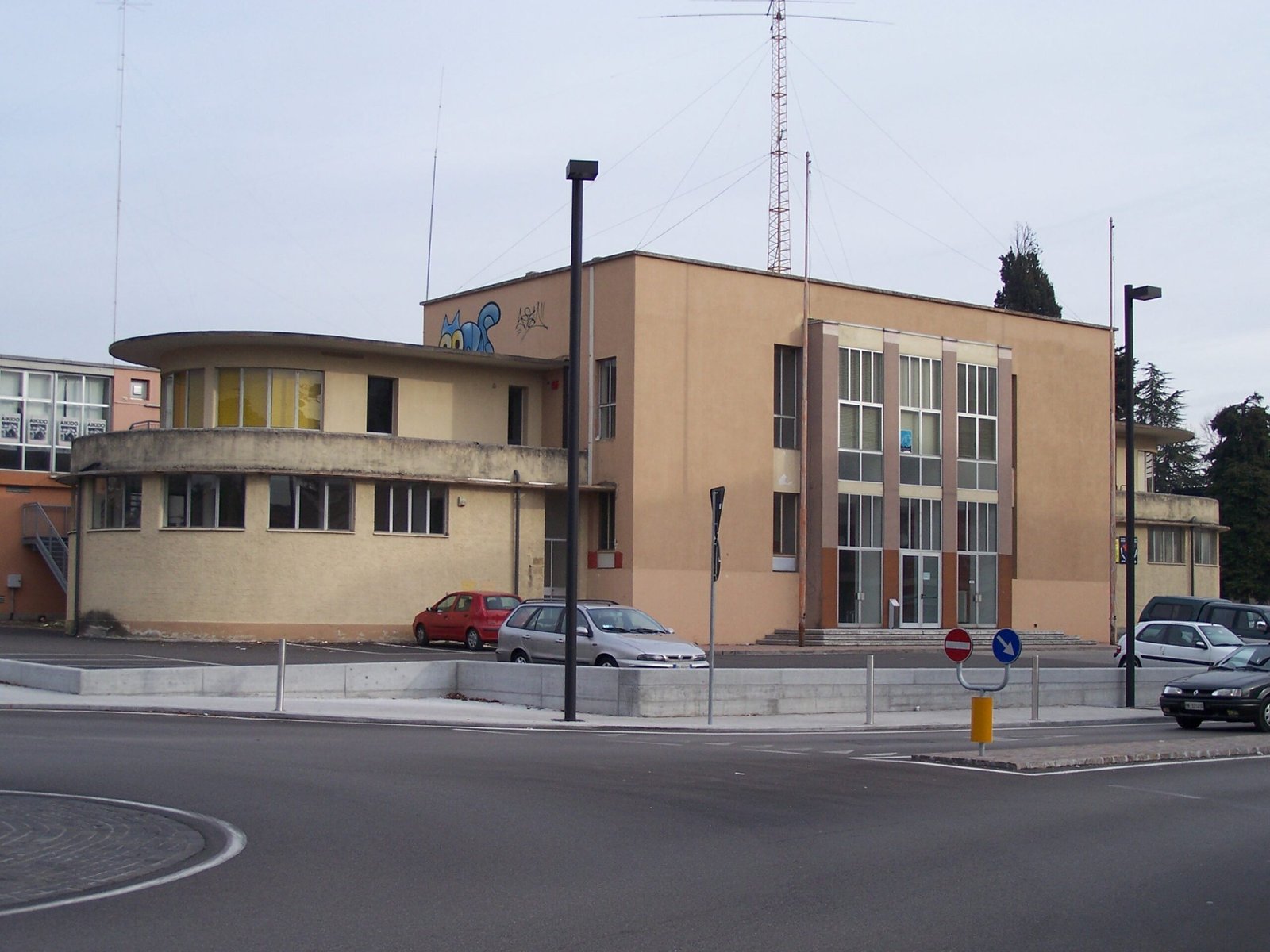 The former Casa del Balilla in Pordenone photographed in 2007, in dull beige render with graffiti on the parapet