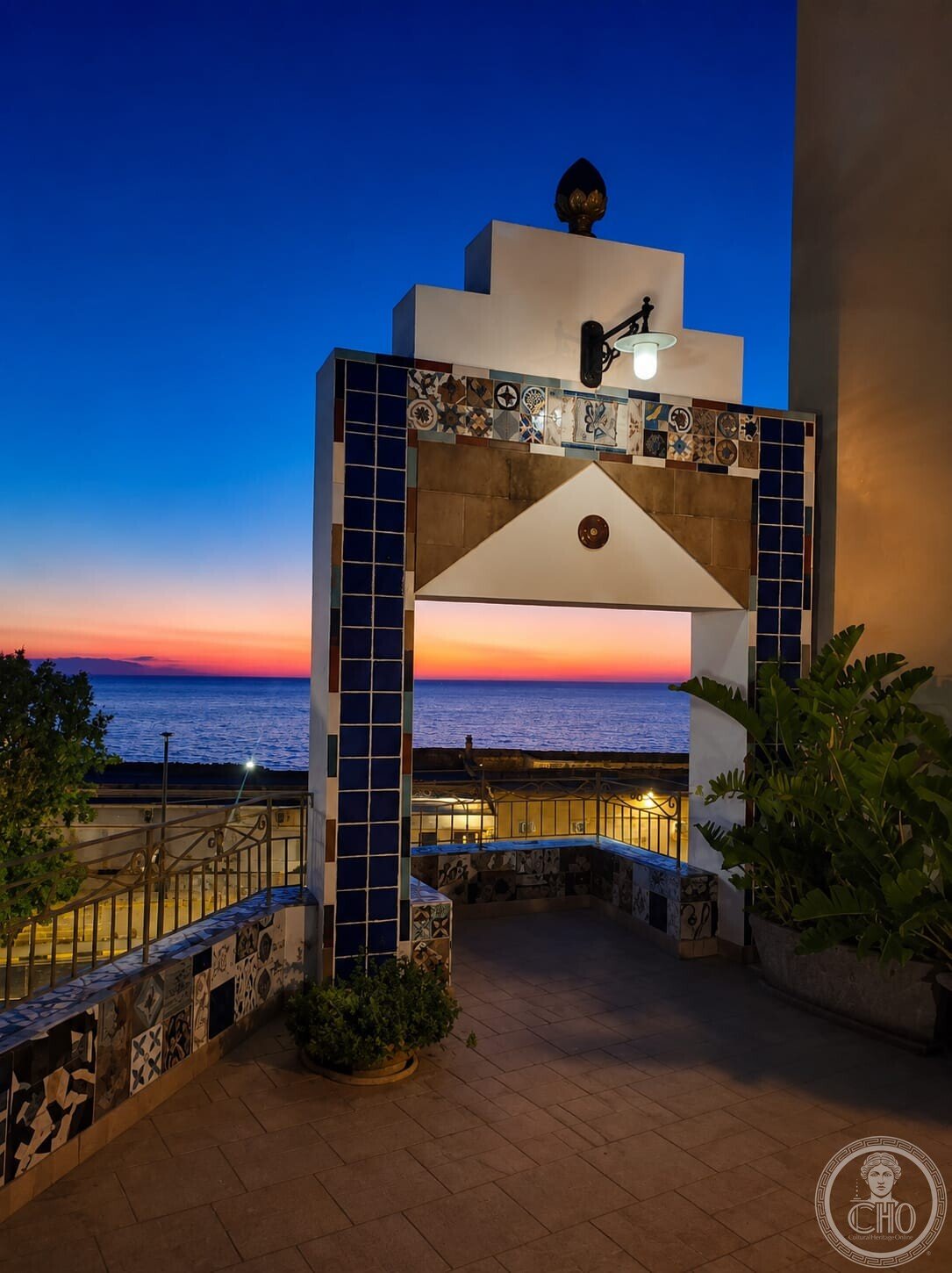 Majolica-clad portal on the terrace of the Casa degli Artisti with the sea at sunset