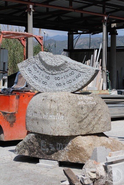 The three granite blocks in the stonemason's yard before installation, the upper slab carved with equations of infinity