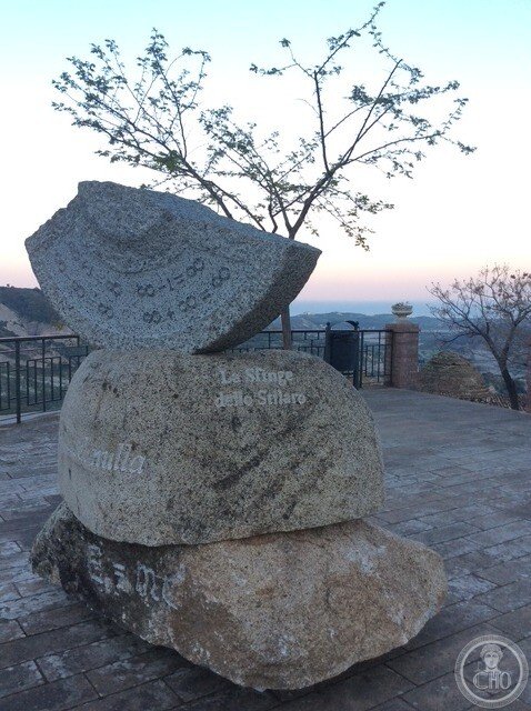 The sculpture at dusk on the terrace, with the railing and the valley behind
