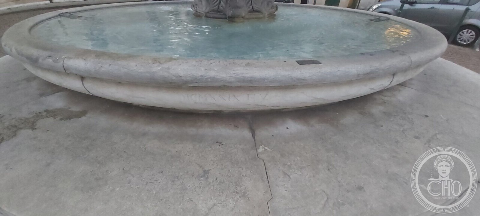 Close view of the inscribed rim of the lower basin of the fountain, showing incised Roman numerals
