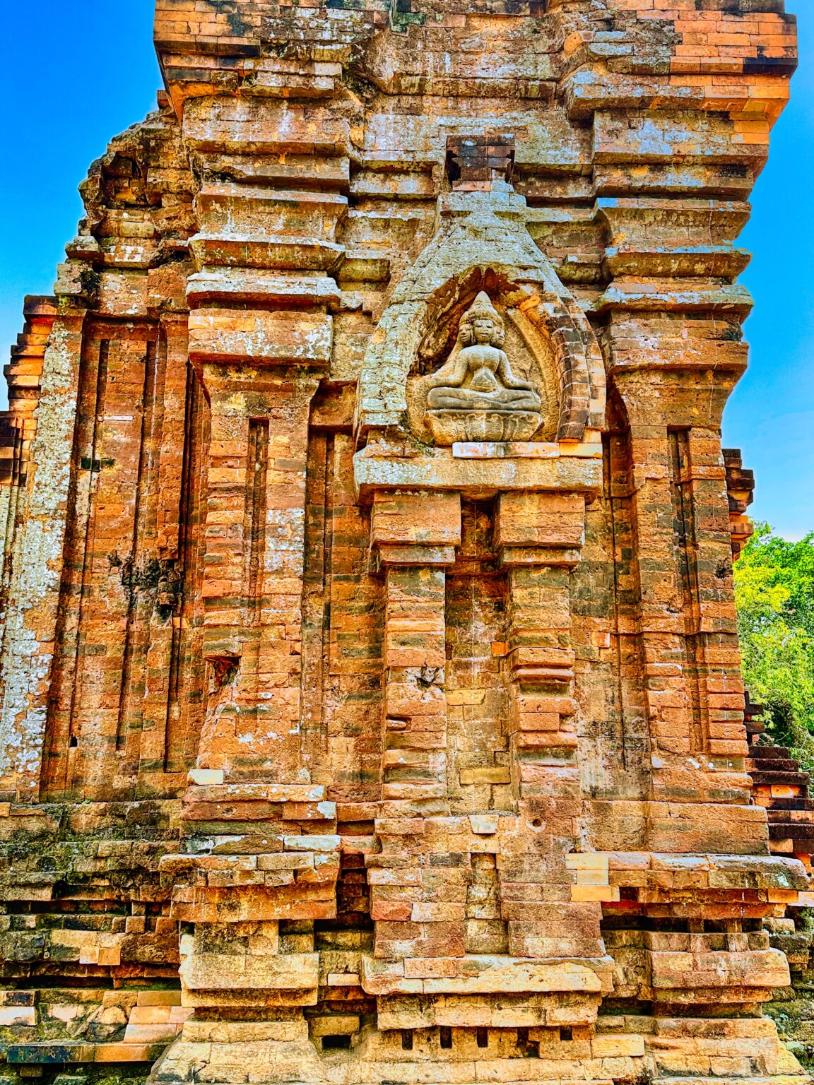 The front of a Cham brick tower at Mỹ Sơn: a tall false door under a carved tympanum, with pilasters and tiers of brick mouldings