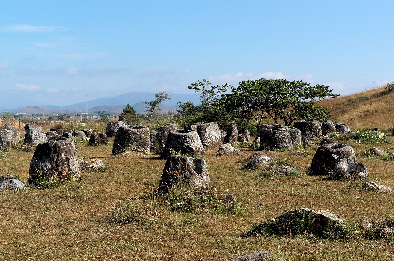 Massive ancient stone jars scattered across plateau grassland at Plain of Jars Site 1 Xieng Khouang Laos
