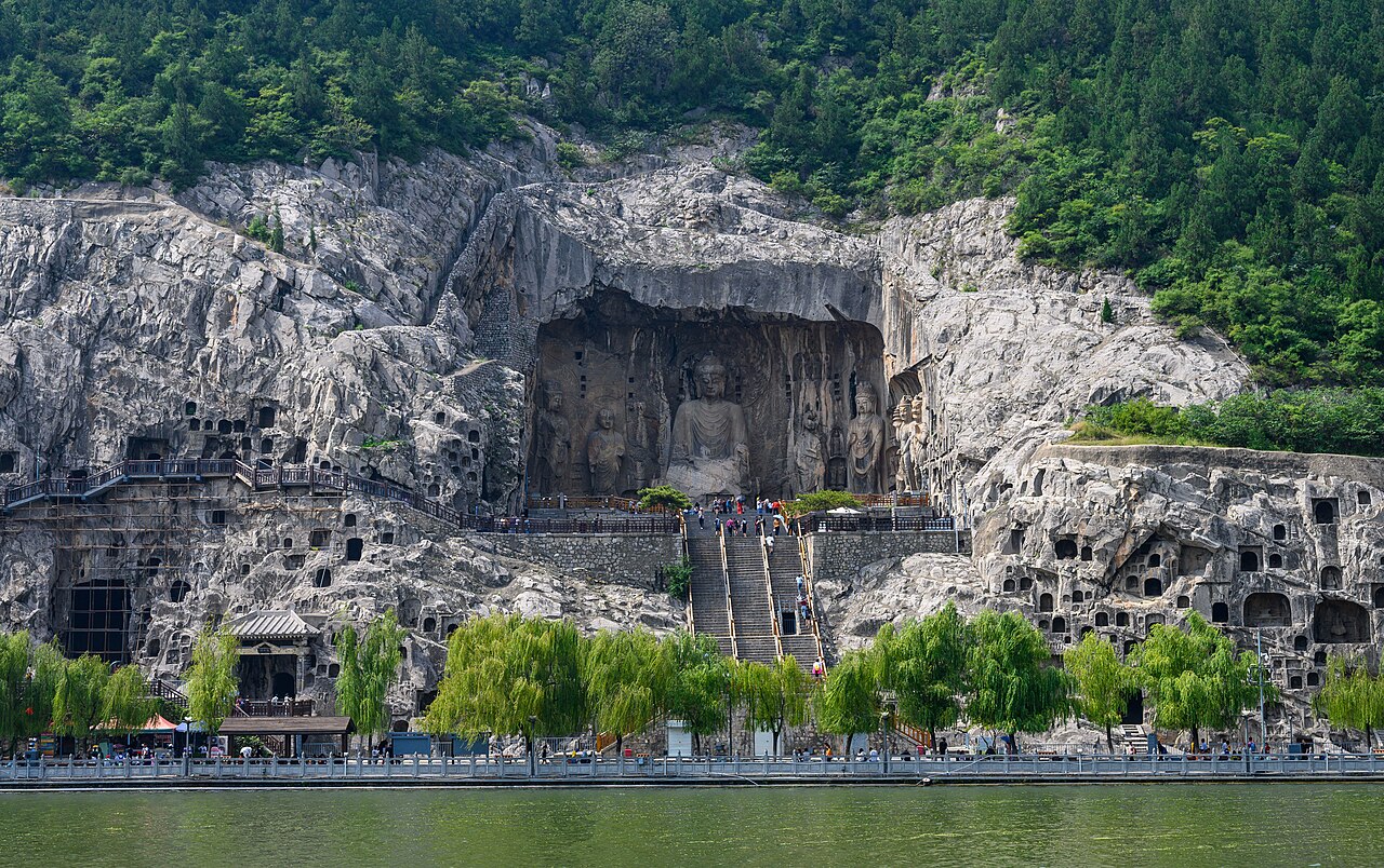 The Fengxian Temple at Longmen Grottoes showing the giant Vairocana Buddha carved into the cliff face with smaller attendant figures, Luoyang, Henan Province, China