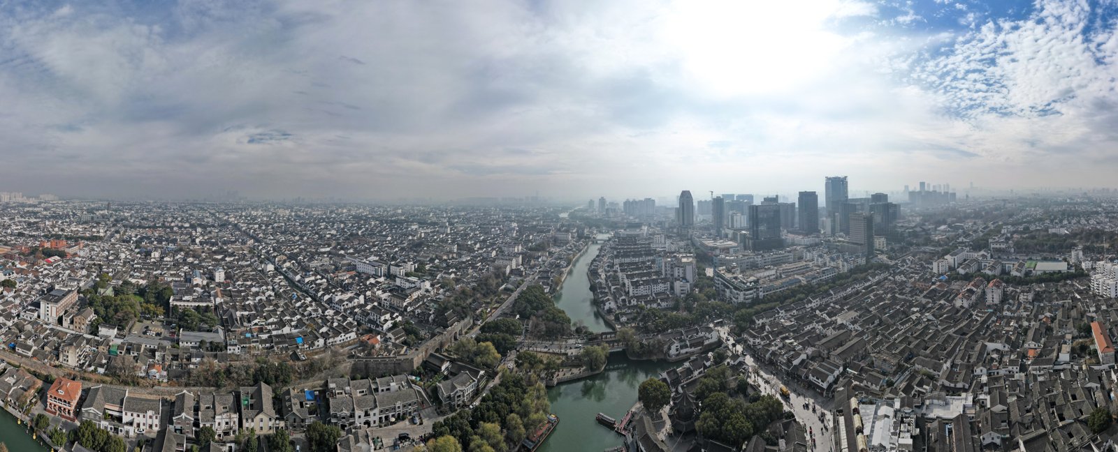 Aerial panorama showing the Grand Canal running through the dense urban fabric of Suzhou