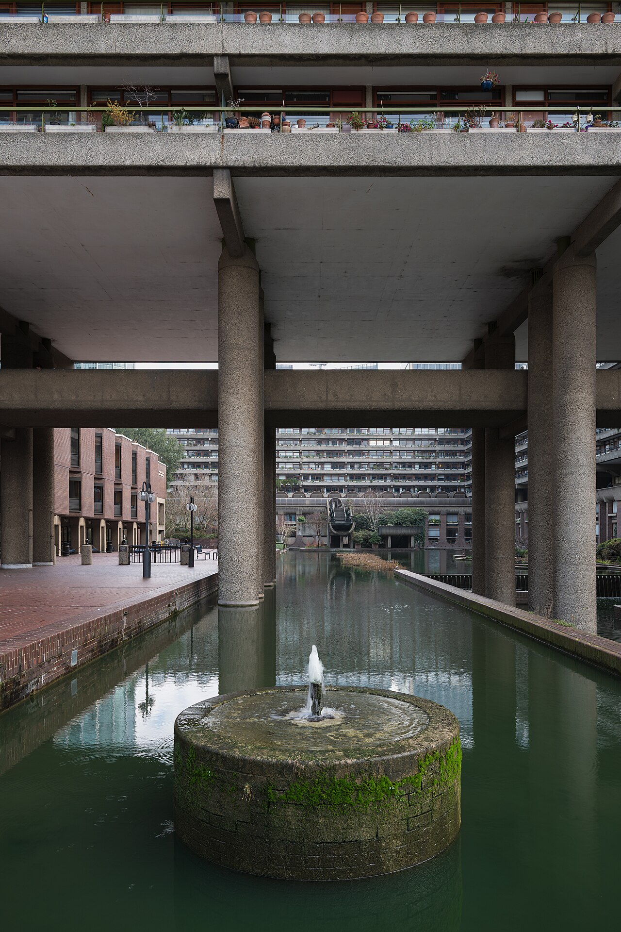 Concrete walkways and towers of the Barbican Estate seen across the lake, City of London