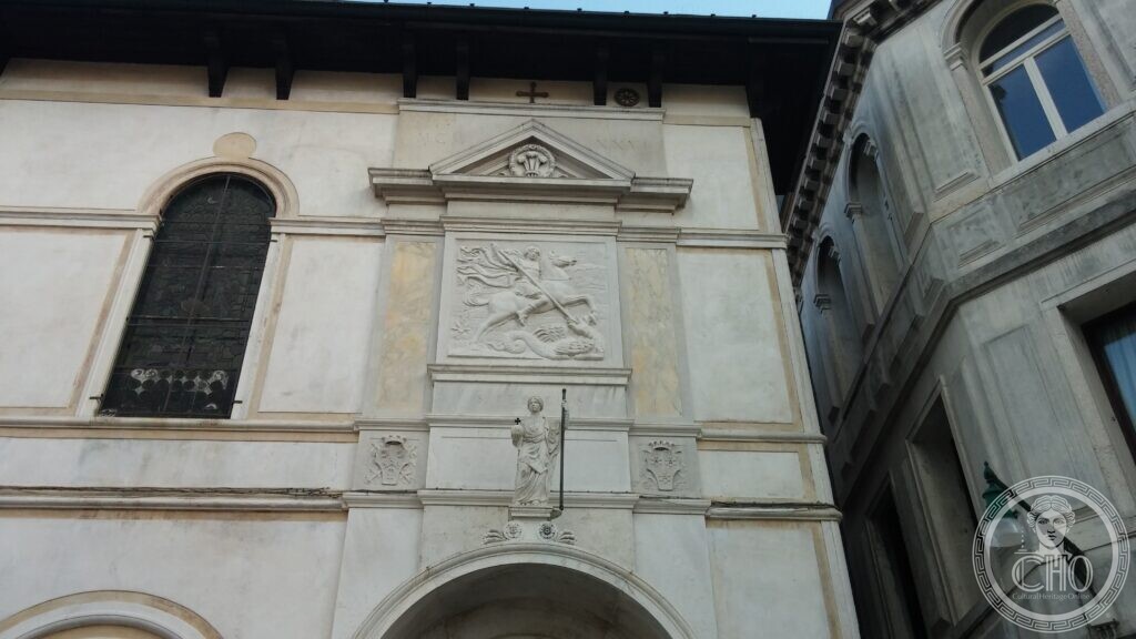 The white stone front of St George's Anglican Church in Venice, a carved relief of Saint George on horseback killing the dragon set in a panel under a pediment, with a statue of the saint below it