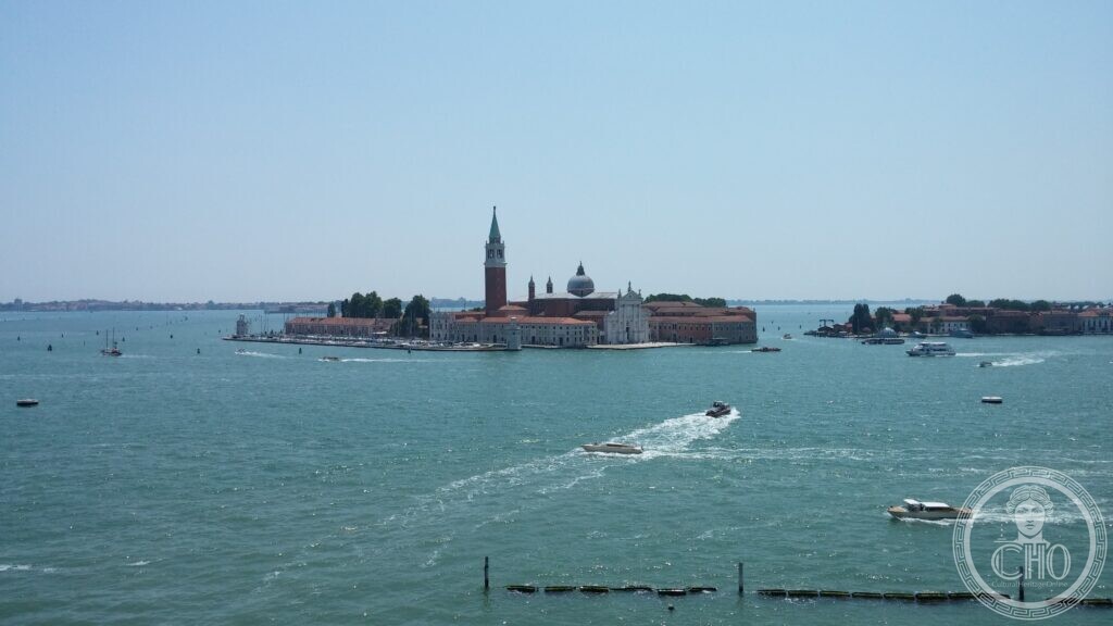 The island of San Giorgio Maggiore across the basin, motor boats crossing the water in the foreground and the lagoon stretching away behind