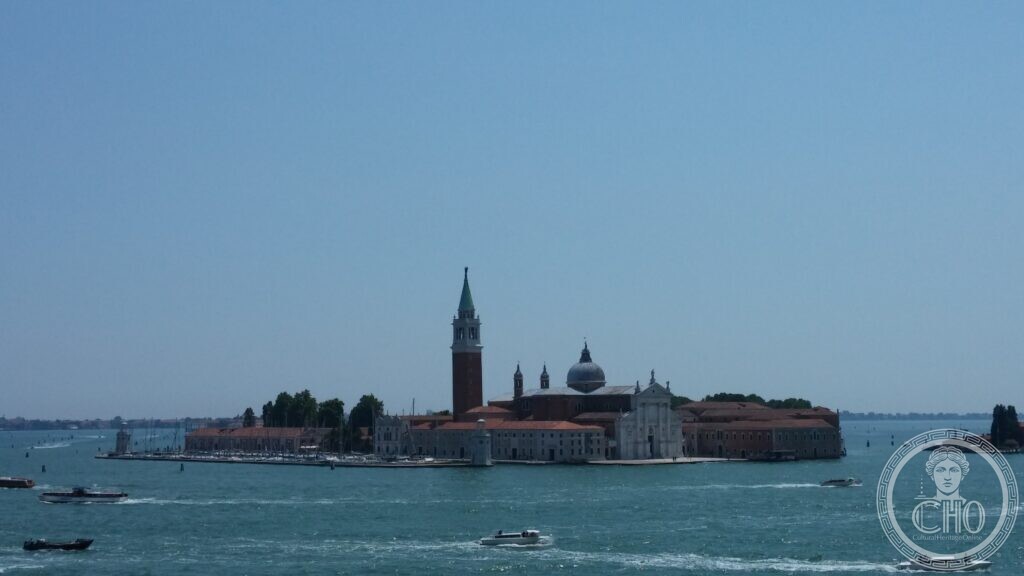 The island of San Giorgio Maggiore seen from above across the water, the campanile and the church front with the long monastery buildings and the marina behind