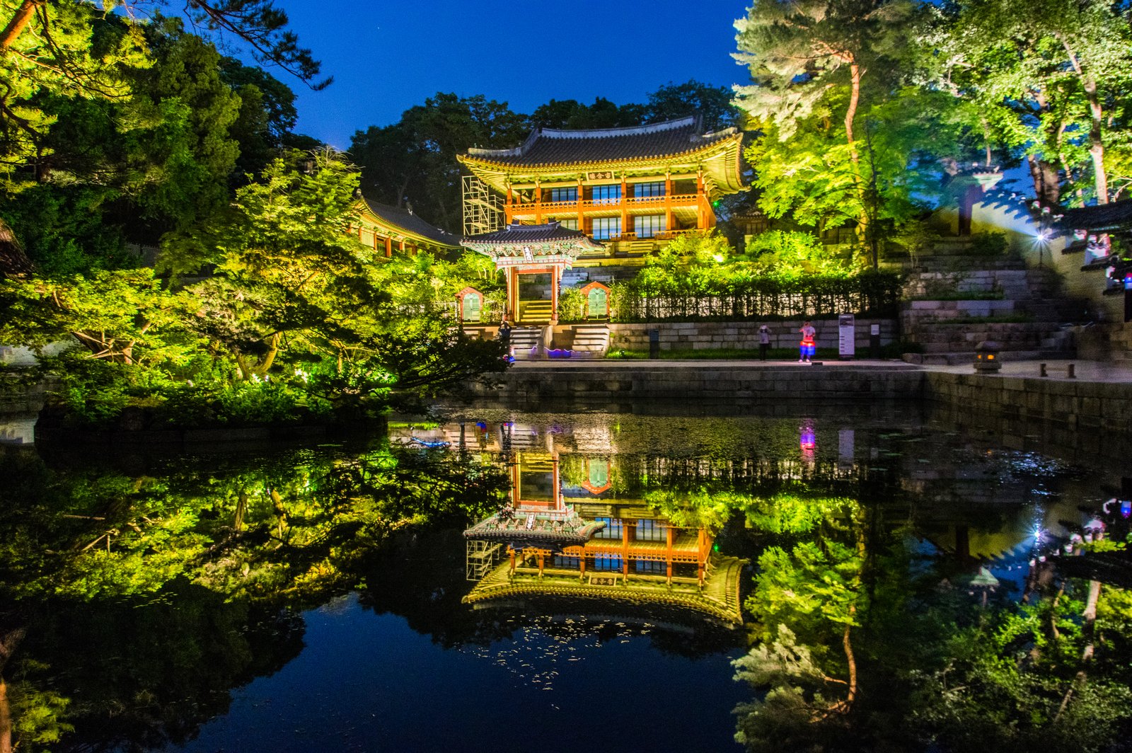 Changdeokgung Palace complex seen from above, showing traditional Korean tiled rooftops surrounded by dense forest in the heart of Seoul