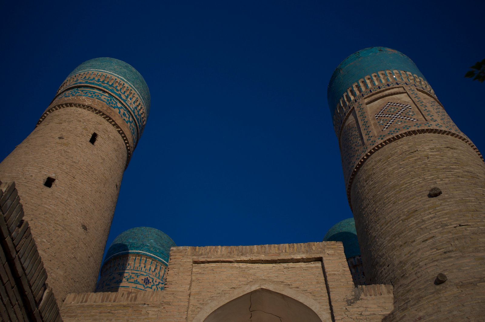 Four blue-domed minarets of the Chor Minor madrasah against a clear sky in Bukhara