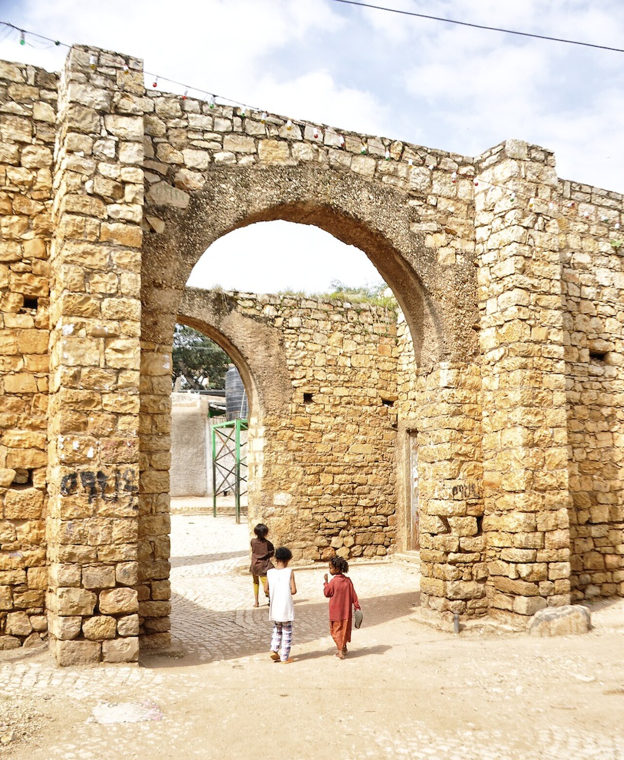 One of the five historic city gates of Harar Jugol — the walled Islamic city of eastern Ethiopia — its whitewashed arch opening into the narrow coloured alleys of the old city, decorated with traditional Harari textile patterns