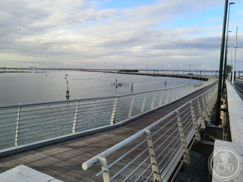 The pedestrian and cycle path along the Ponte della Libertà, a timber deck with white railings curving away across the lagoon towards the mainland