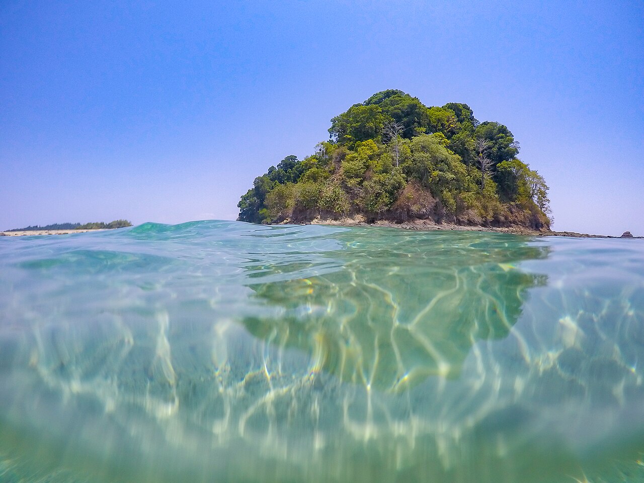 Aerial view of Coiba Island Pacific coast with dense rainforest meeting turquoise water