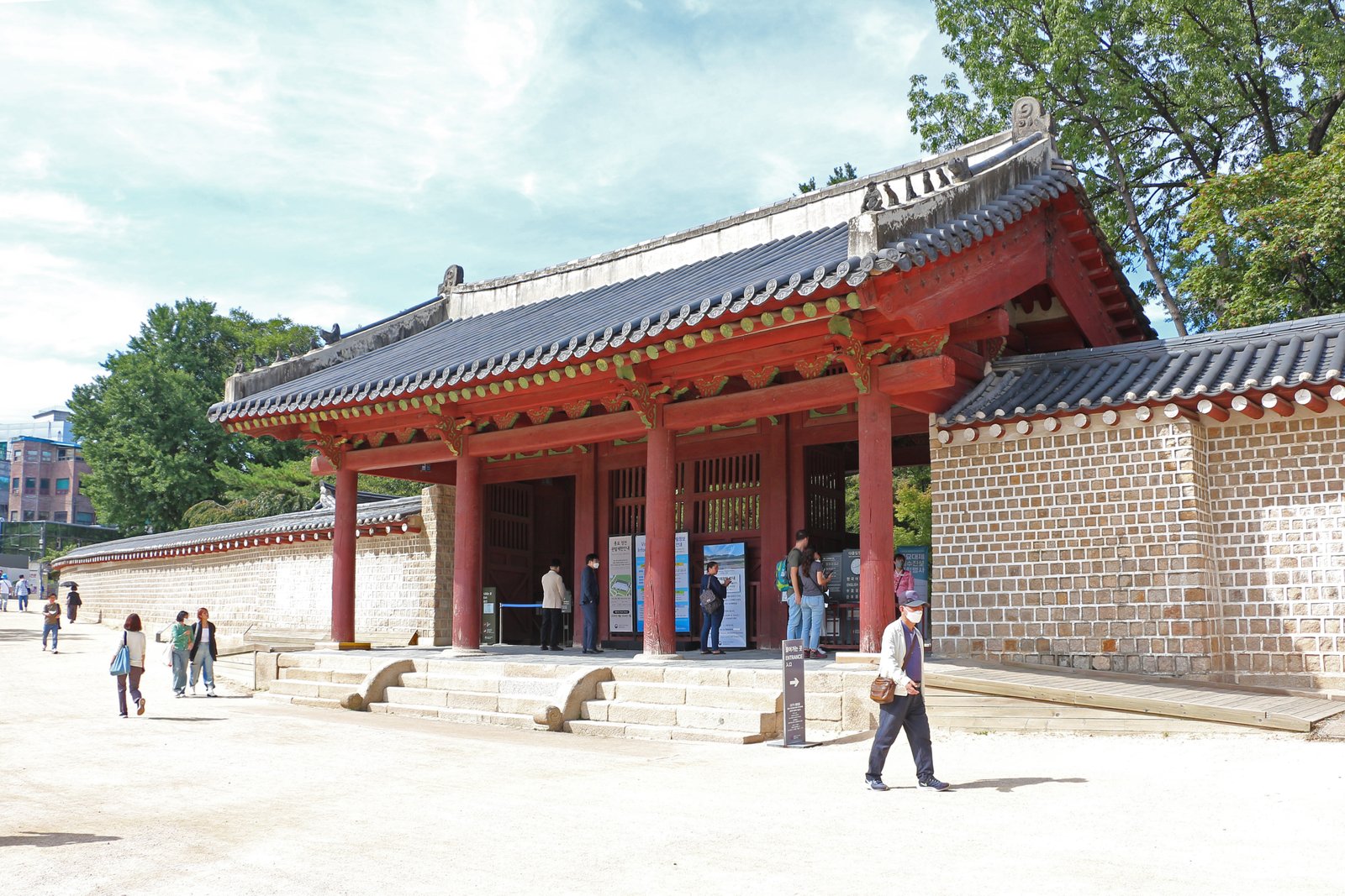 Entrance gate of Jongmyo Shrine in Seoul, a low wooden gate with a sweeping tiled roof set in a forested compound