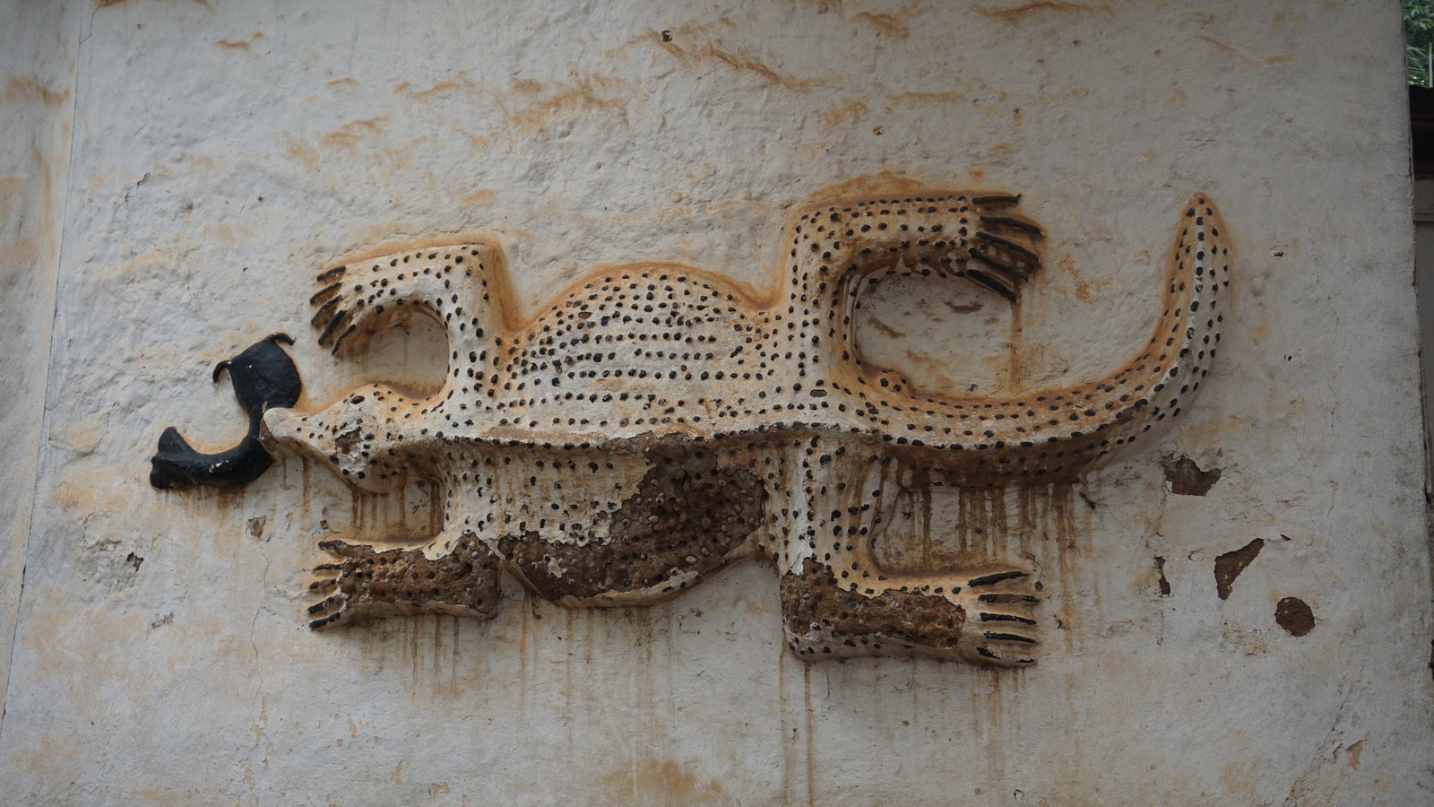 Exterior of Kentikrono shrine, an Asante traditional building with decorative earth walls and carved wooden elements