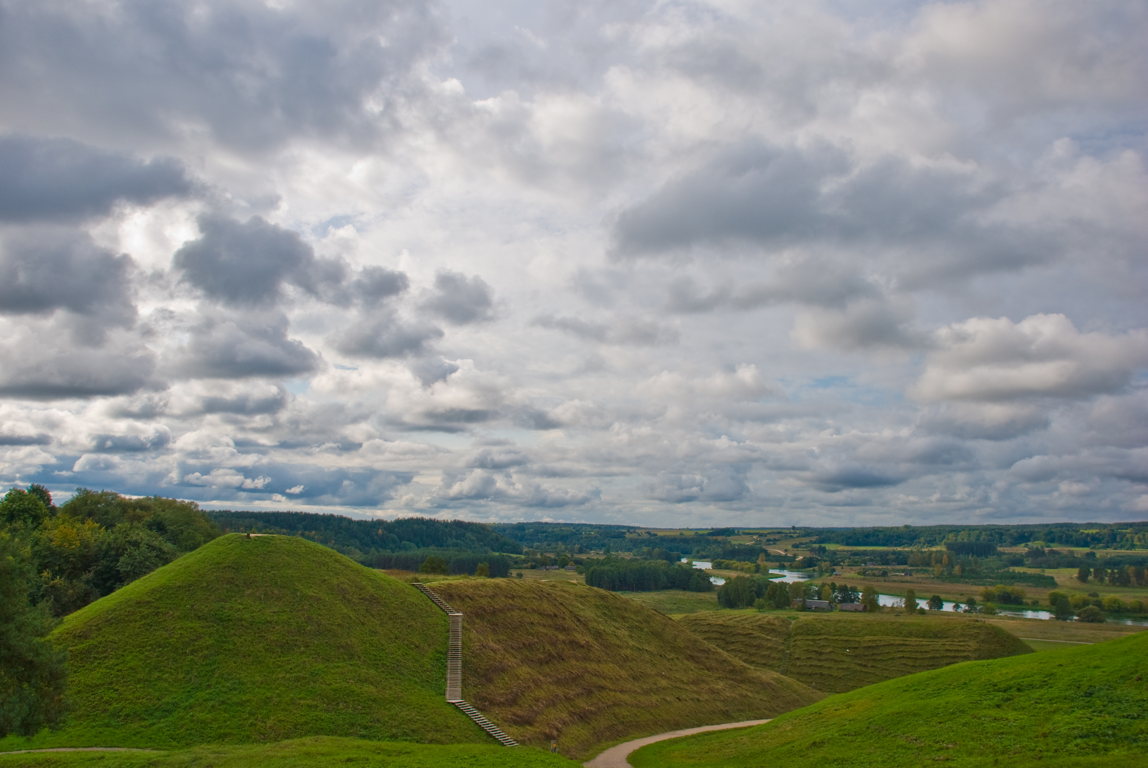 Four grass-covered Iron Age hillfort mounds rising above the Neris River valley at Kernavė