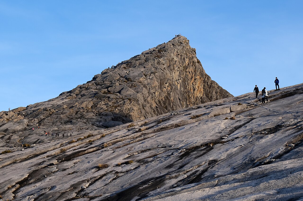 Climbers on the rocky granite summit of Low's Peak, Mount Kinabalu at dawn